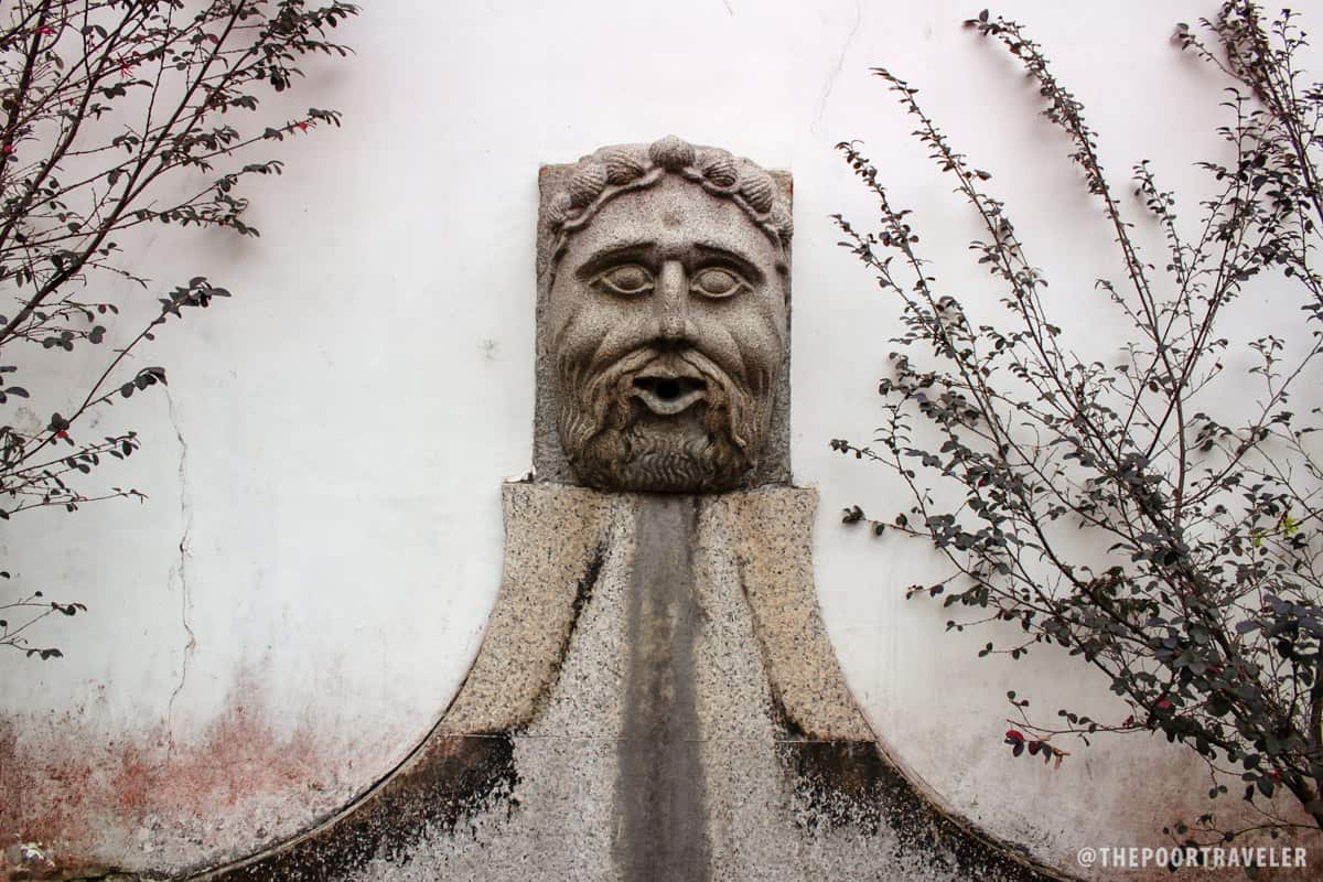 An old water fountain on the wall surrounding the garden